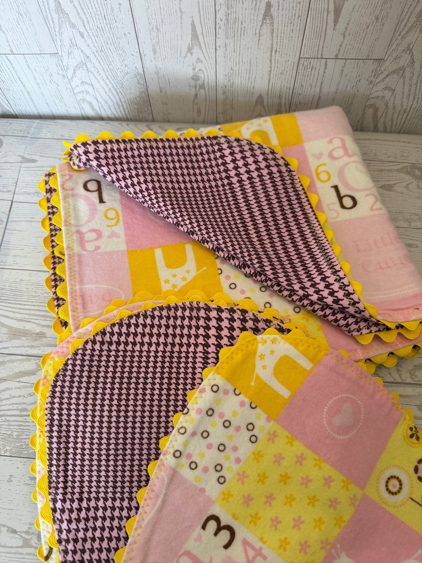 Handmade pink and yellow alphabet flannel baby blanket with houndstooth reverse and yellow ric-rac edging