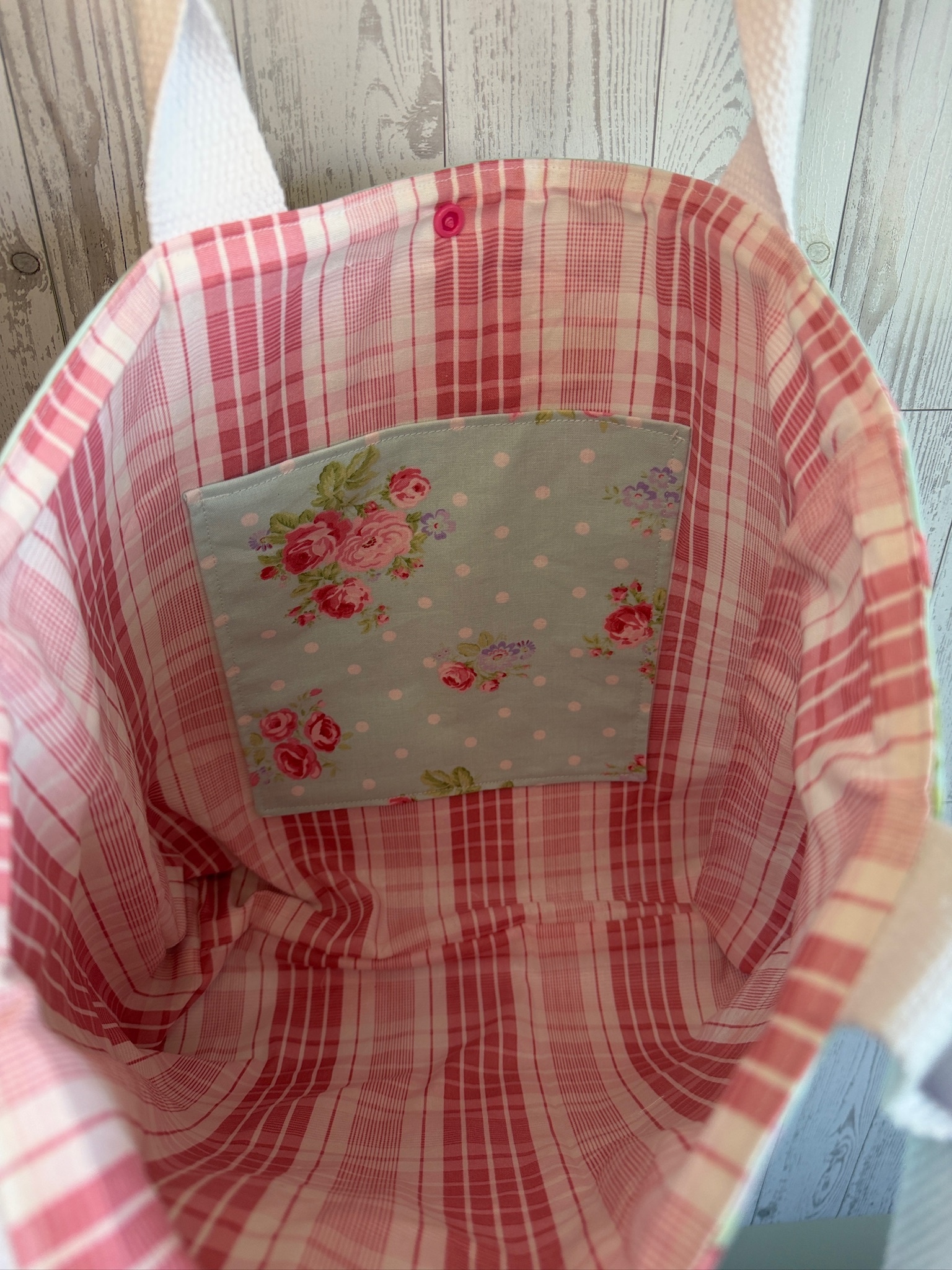 Interior of the mint rosebud tote bag showing pink plaid lining and a floral slip pocket