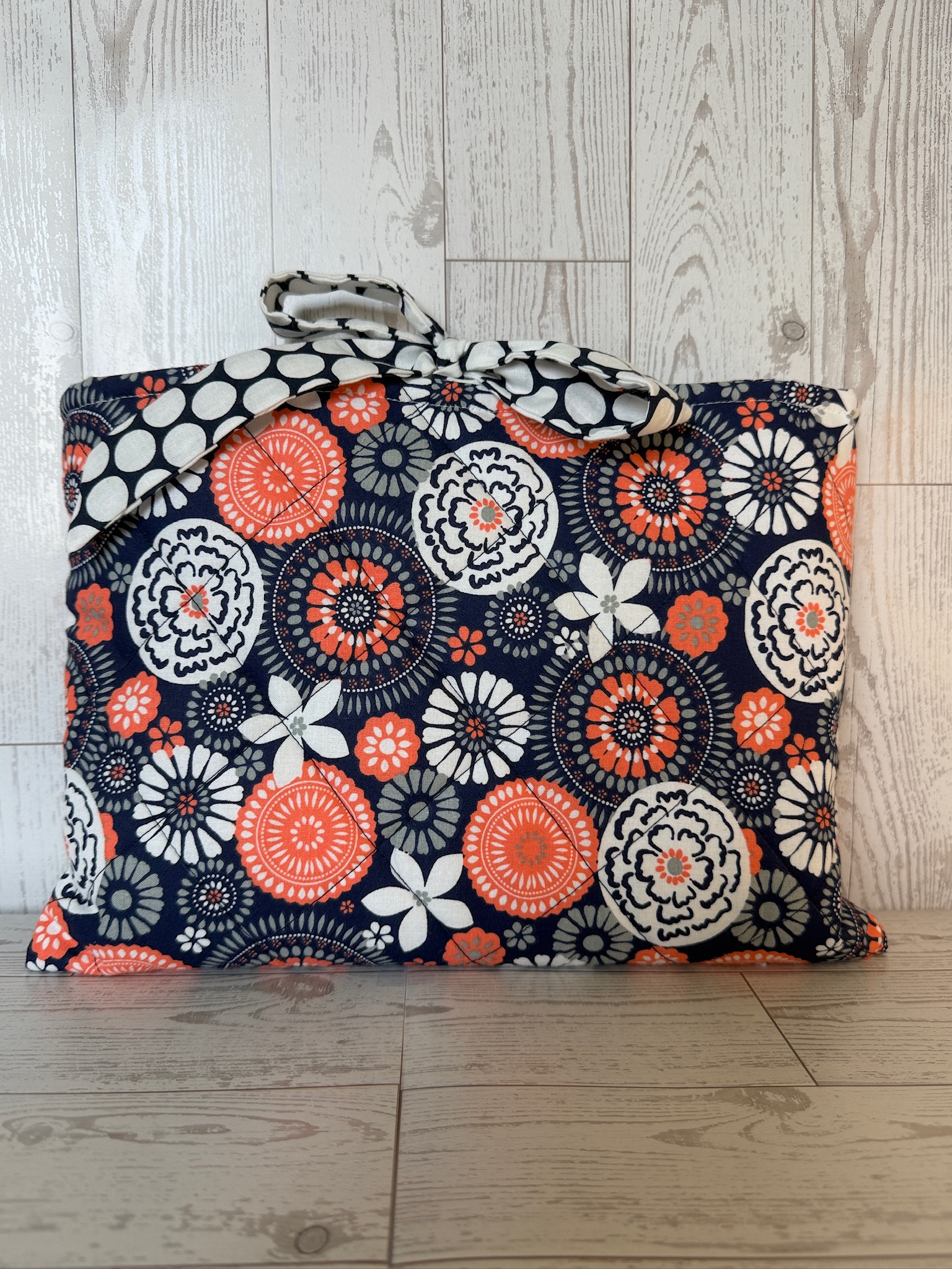 Navy floral book sleeve shown upright with its metal clip closure at the top