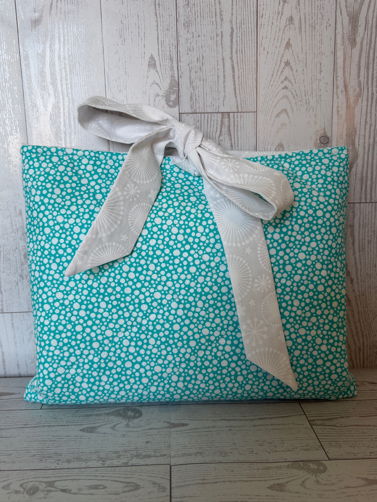 Handmade aqua ditsy floral padded book sleeve tied closed with a white fabric bow