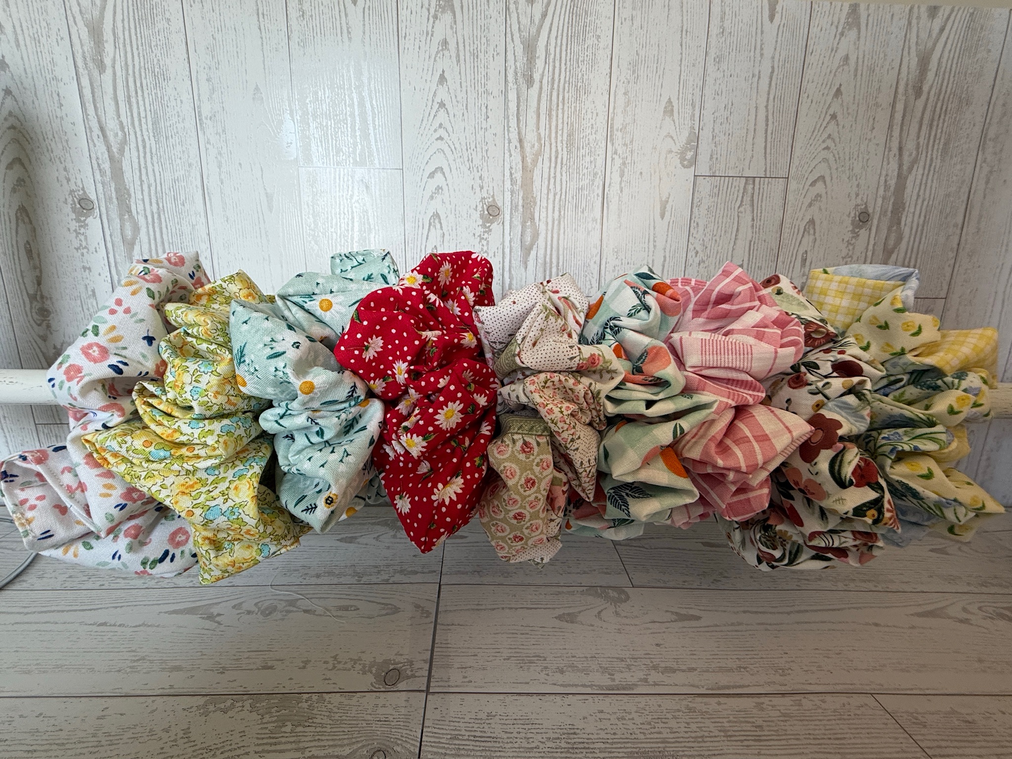 Row of handmade fabric scrunchies in ditsy floral, red strawberry, daisy mint and yellow gingham prints