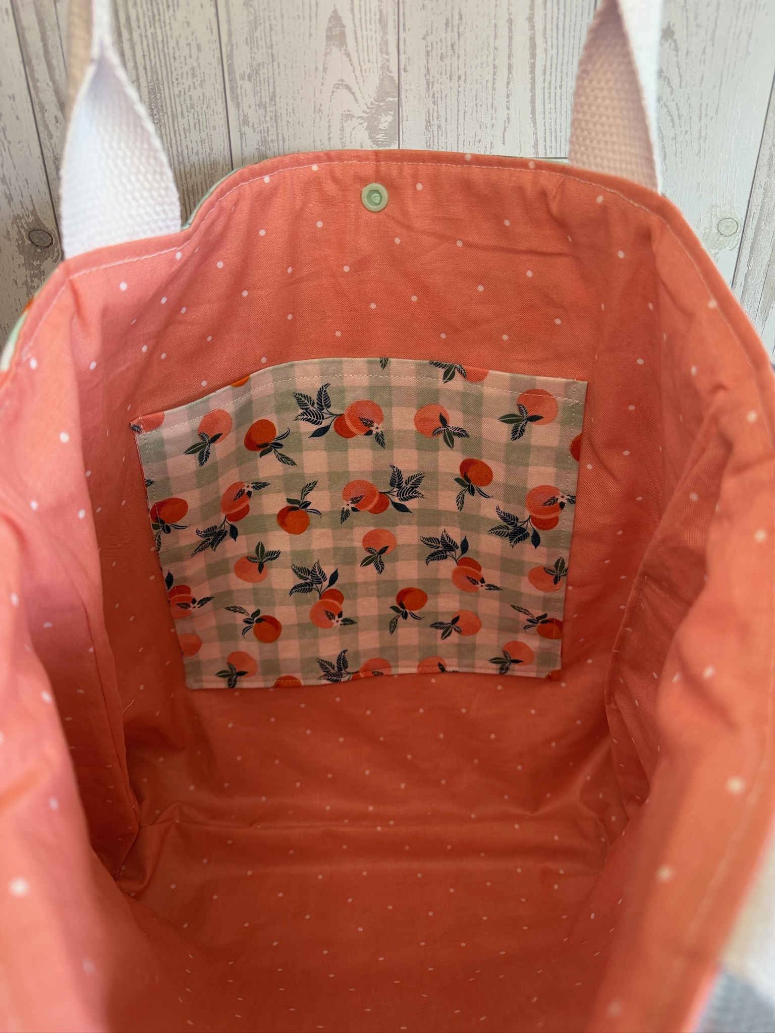 Interior of the clementine tote bag showing coral lining and an orange gingham slip pocket