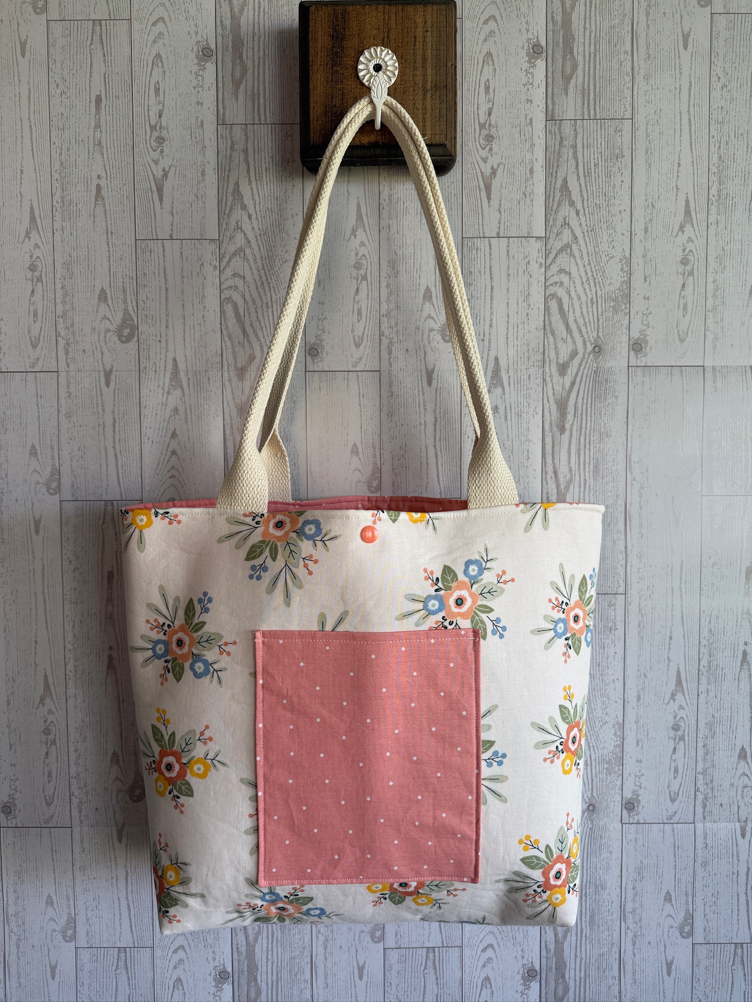Handmade cream floral tote bag with a rose pink front pocket and natural webbing straps