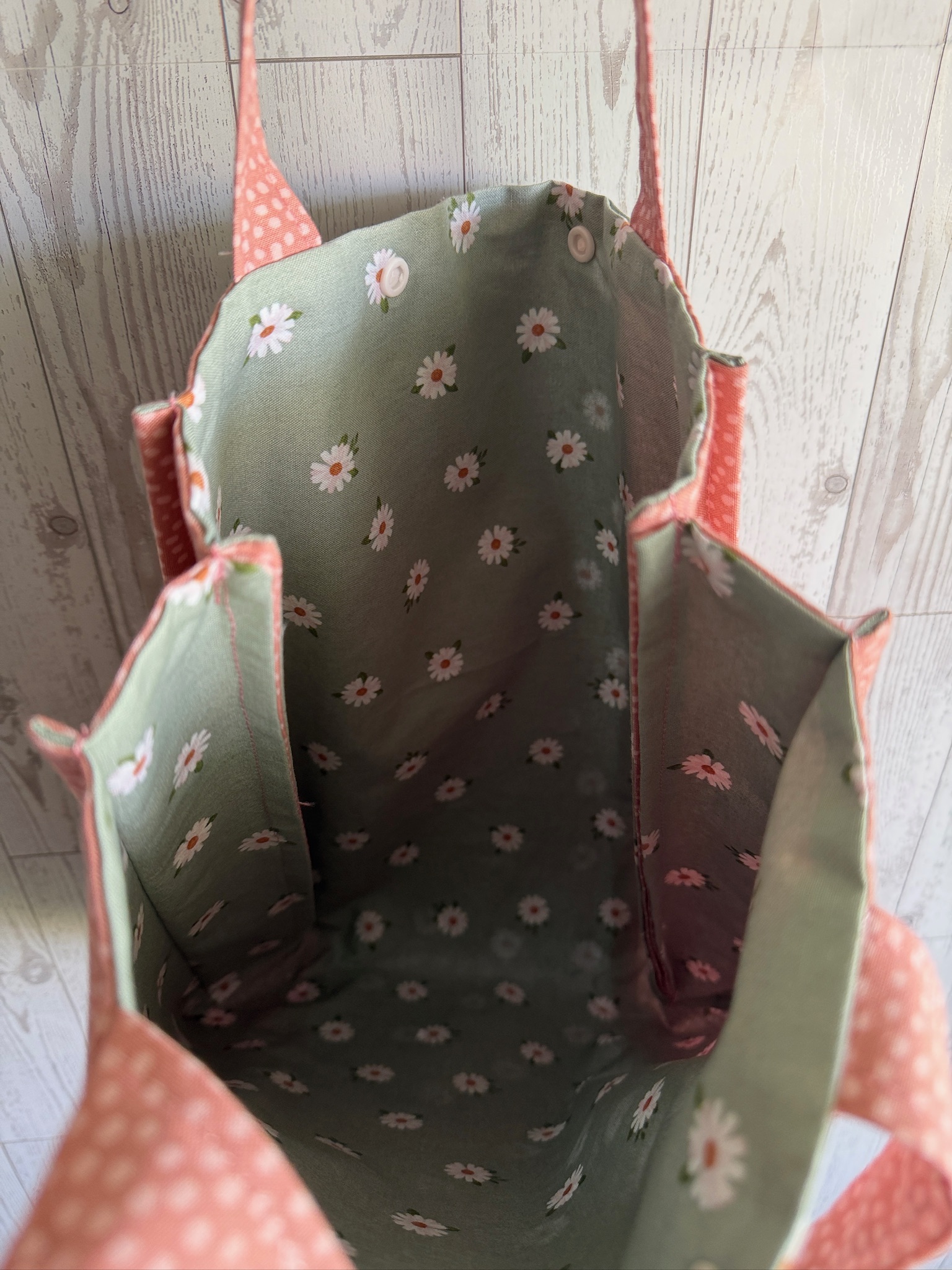 Interior of the sage daisy tote bag showing floral lining and a pink slip pocket