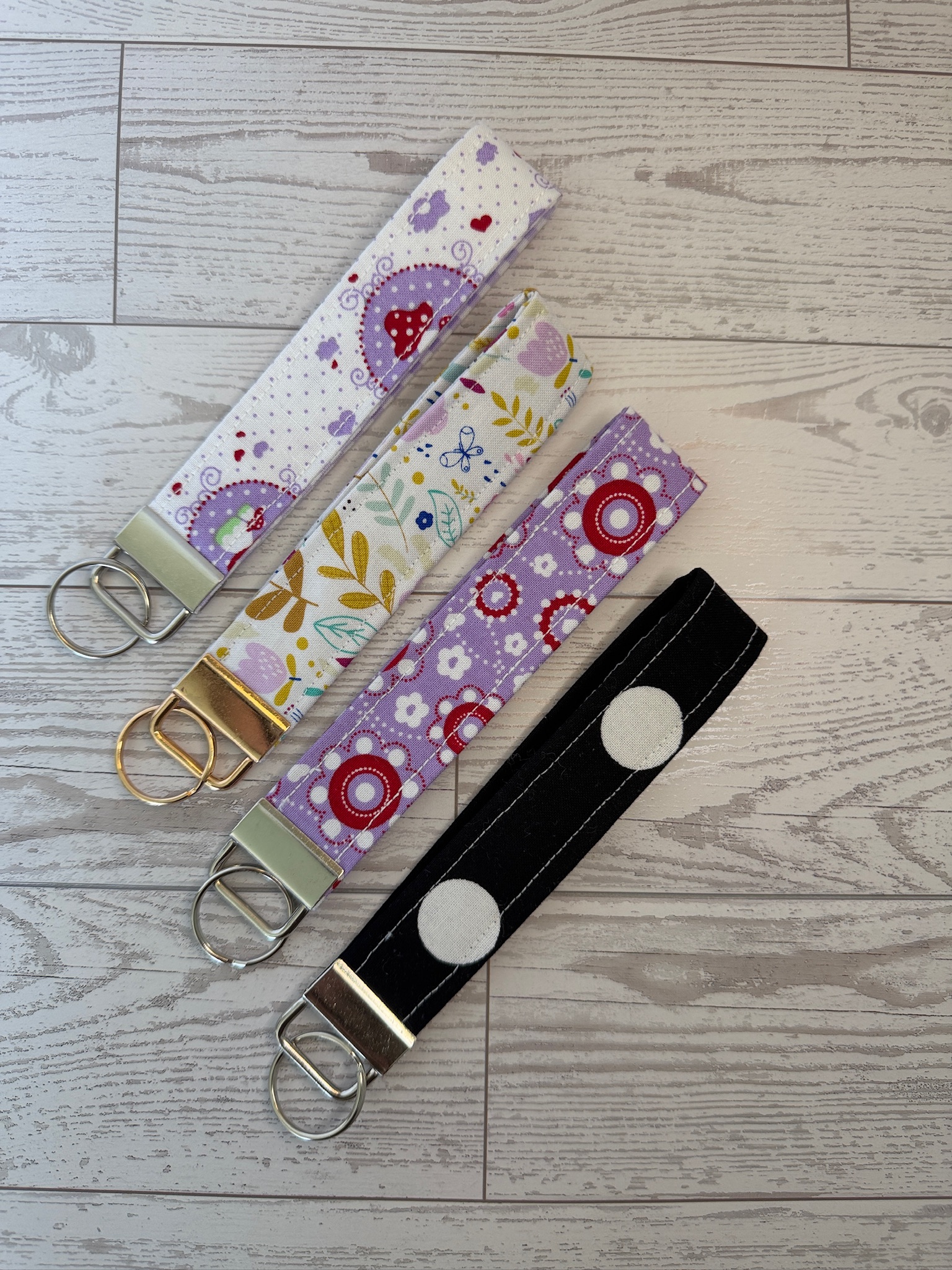 Four handmade key fob wristlets in lavender medallion, mushroom, folk floral and black polka dot prints