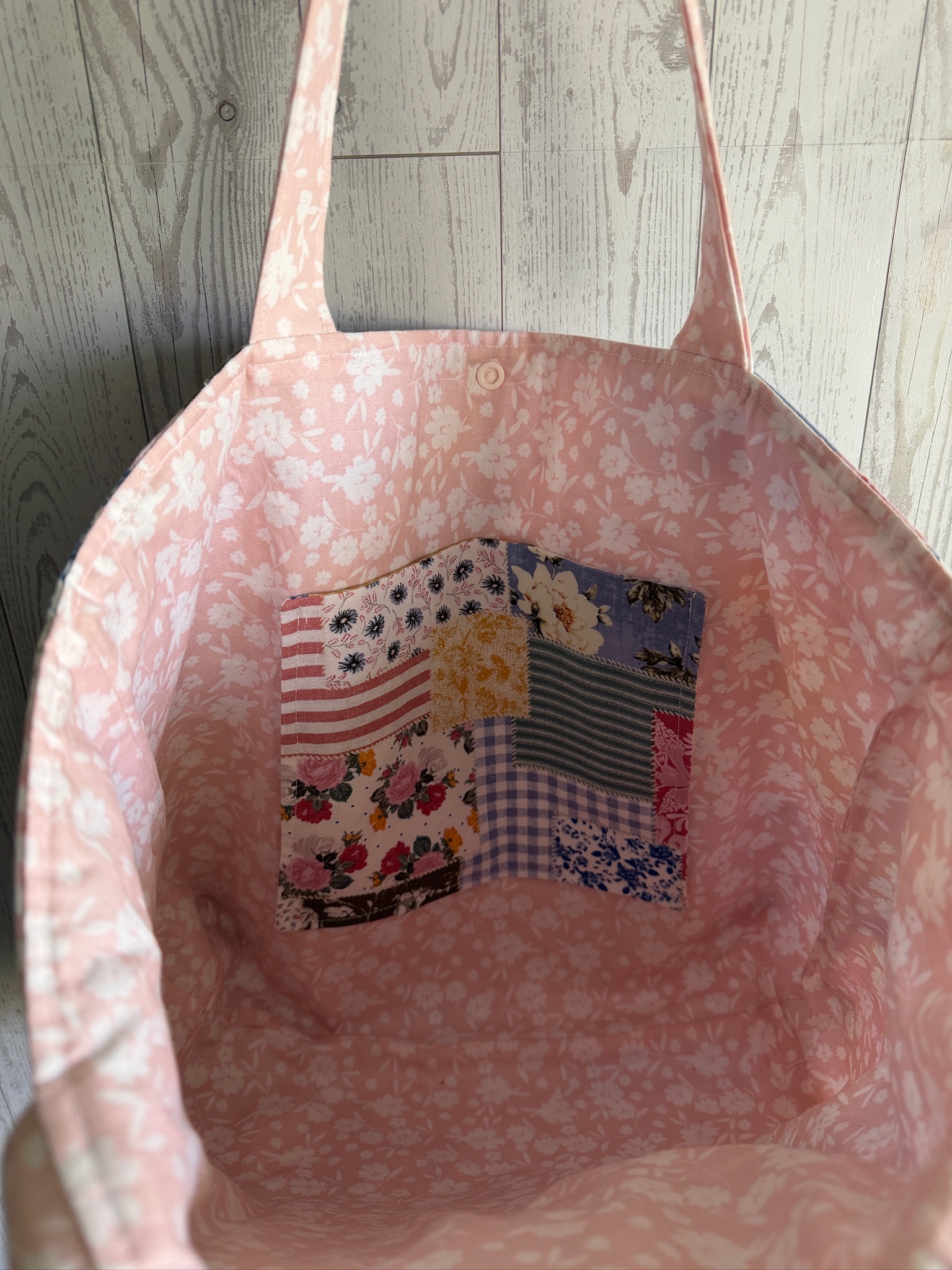 Interior of the patchwork tote bag showing pink floral lining and a patchwork slip pocket