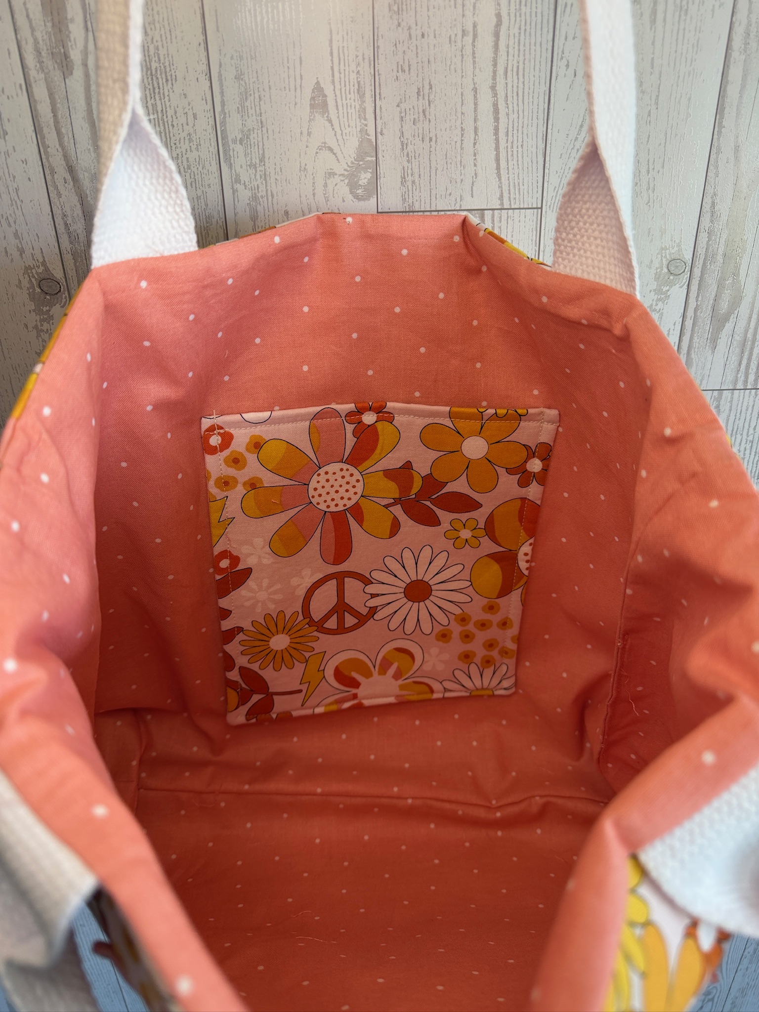 Interior of the retro floral tote bag showing coral polka dot lining and a retro print slip pocket