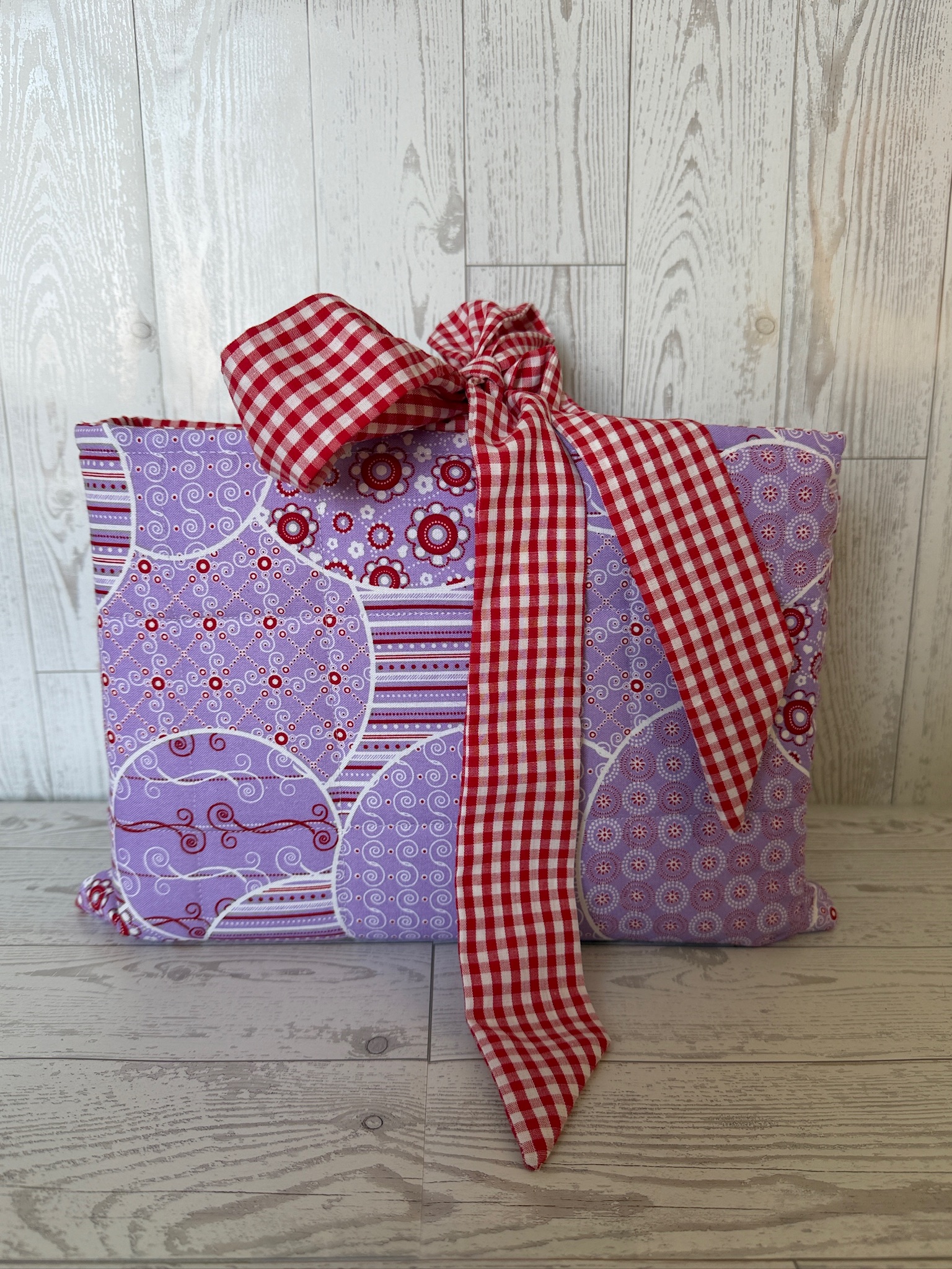 Handmade lavender medallion print padded book sleeve tied closed with a red gingham bow