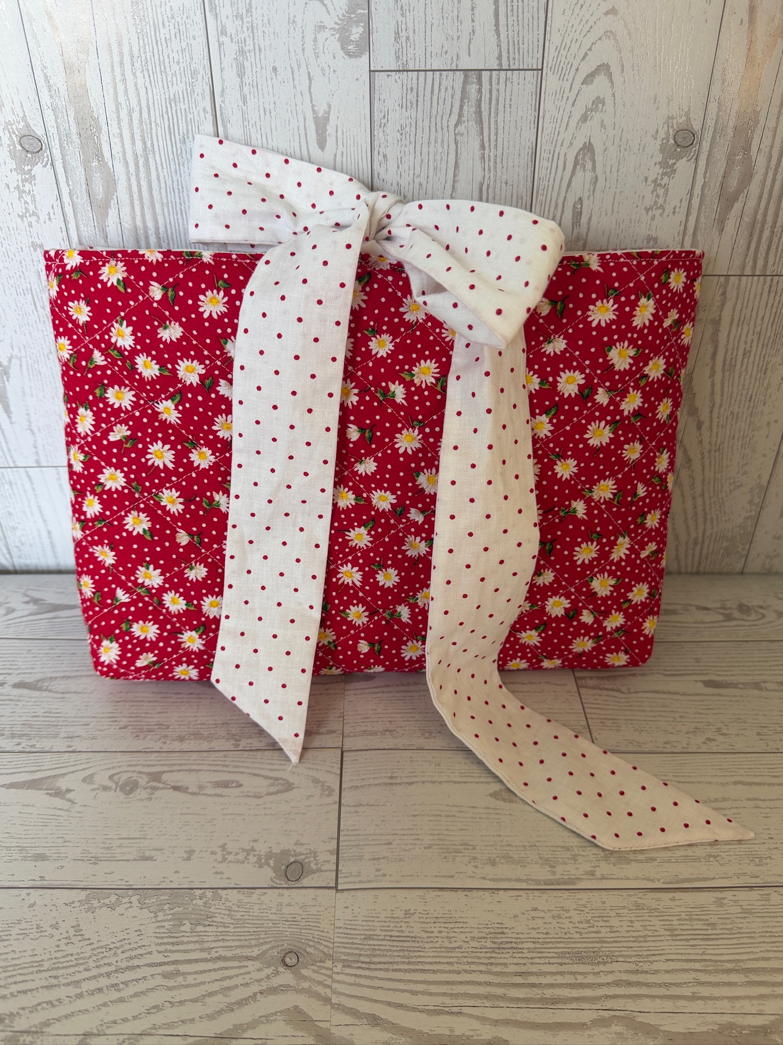 Two handmade red calico floral book sleeves with cream polka dot fabric ties